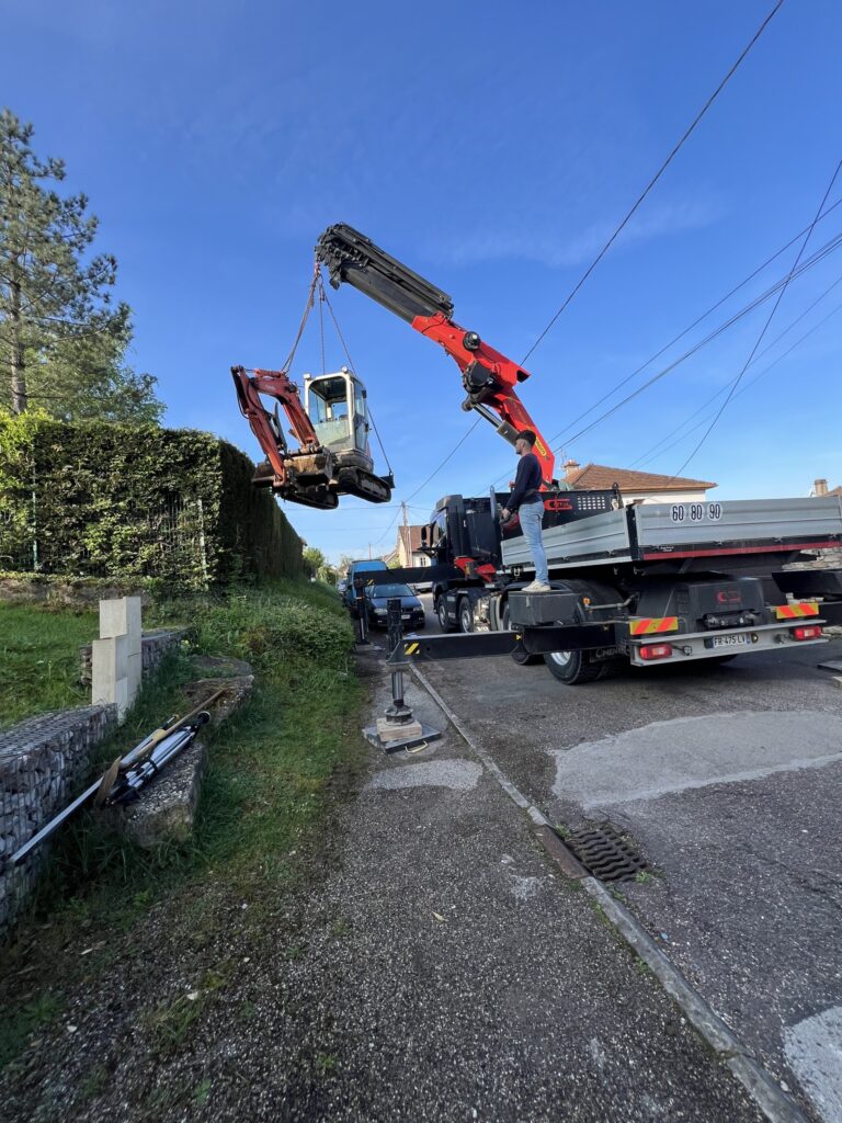 bde-terrassement - camion avec grue de levage lève un engin de chantier